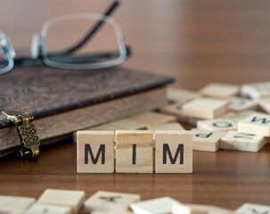 the acronym mim for masters in management word or concept represented by wooden letter tiles on a wooden table with glasses and a book - obrazy, fototapety, plakaty