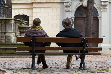 Ehepaar auf Bank wartend und auseinander sitzend, Mann und Frau oder Paar