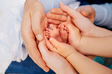 winzige Füße eines Neugeborenen in den Händen liebevoller Eltern - obrazy, fototapety, plakaty