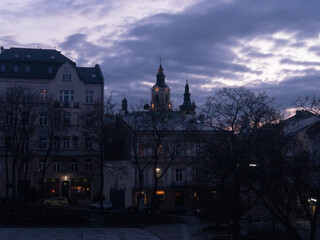 Obraz premium Twilight colours of night Przemysl at Poland at Wladycze street. View is from museum of bells and tobacco pipes to the lights of bell tower and clock near Roman Catholic archicathedra in the Gothic 