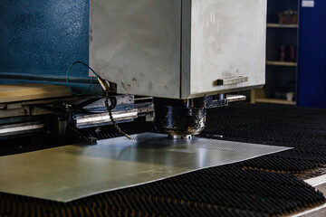 CNC punching and nibbling machine and perforated steel sheet, close up