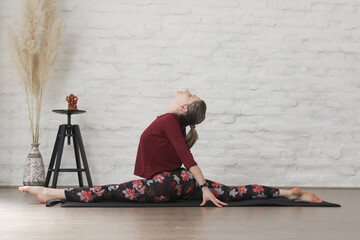 Young woman practicing stretching yoga positions. Wellbeing and self care concept.	