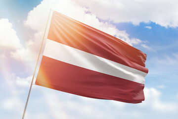 Sunny blue sky and a flagpole with the flag of latvia