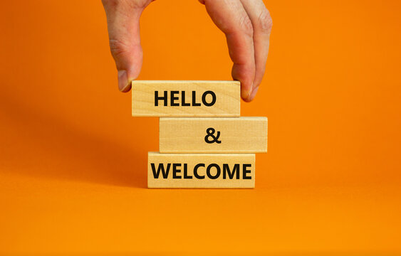 Hello And Welcome Symbol. Concept Words Hello And Welcome On Wooden Blocks. Businessman Hand. Beautiful Orange Table Orange Background. Business Hello And Welcome Concept. Copy Space.