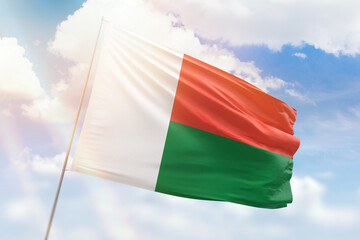 Sunny blue sky and a flagpole with the flag of madagascar