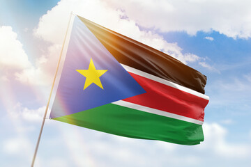 Sunny blue sky and a flagpole with the flag of south sudan