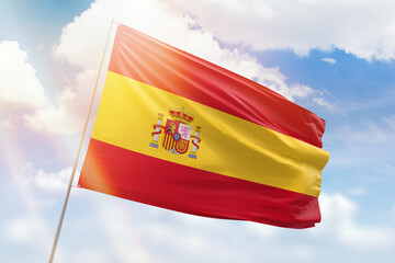 Sunny blue sky and a flagpole with the flag of spain