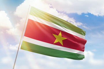 Sunny blue sky and a flagpole with the flag of suriname
