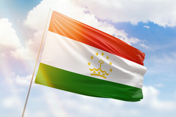 Sunny blue sky and a flagpole with the flag of tajikistan