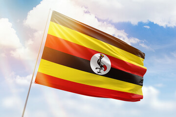 Sunny blue sky and a flagpole with the flag of uganda