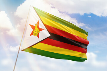 Sunny blue sky and a flagpole with the flag of zimbabwe