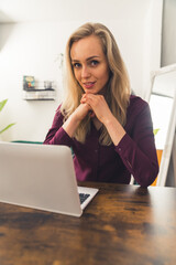 Obraz premium love my remote job - blonde girl sitting at the table and working from home remote job concept medum closeup living room vertical . High quality photo