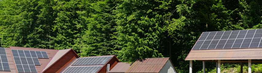 Fototapeta na wymiar Solar panels on the roof of a cottage in the forest. Eco technology panoramic background. Electricity generation background. Renewable energy pattern.