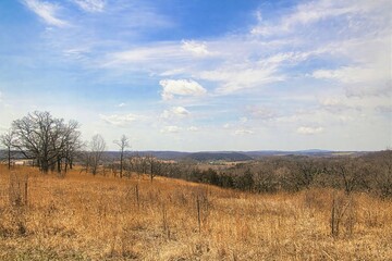 Obraz premium The view beneath blue sky and white clouds on a Spring day atop a bluff along the Ice Age Trail overlooking the forests, farms and fields of Southern Wisconsin.
