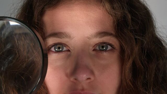 Young girl looking through a magnifying glass 