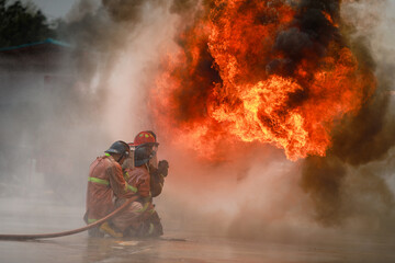 Obraz premium firefighter training firemen practice fighting the fire.fireman using water and extinguisher to fighting with fire flame in an emergency,fireman team fire drills.