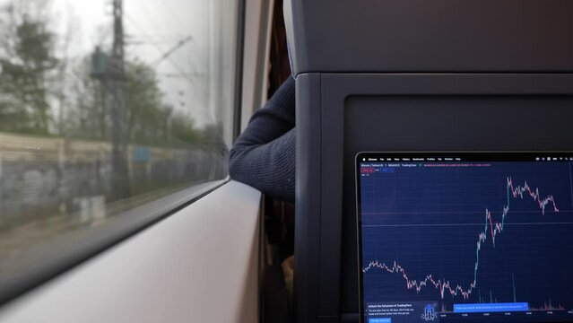 Berlin, Germany - APRIL 2022: Working as trader or stock trading on the train during commute.Using trading view app on MacBook laptop in the train.