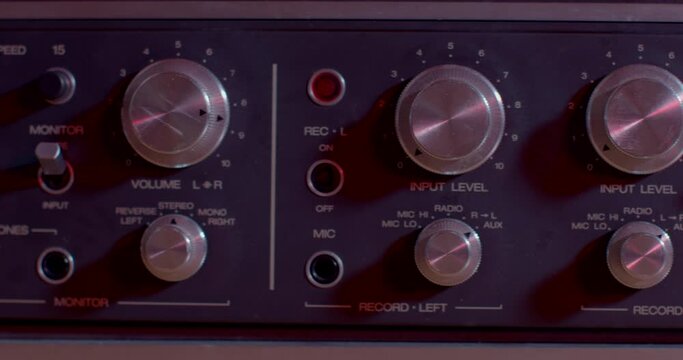 Front side of a vintage tape recorder for audio playback. Control elements of the device, setting frequencies, channel strengths. Using the sound sensor.