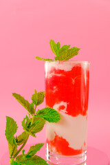 Strawberry cocktail.Berry smoothies. cocktail and cream in a transparent glass goblet with strawberries and sprigs of mint on a pink background.Summer cocktails and drinks.