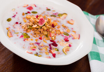 Sweet granola with dried fruits, pumpkin seeds and nuts served with milk as tasty and healthy breakfast..