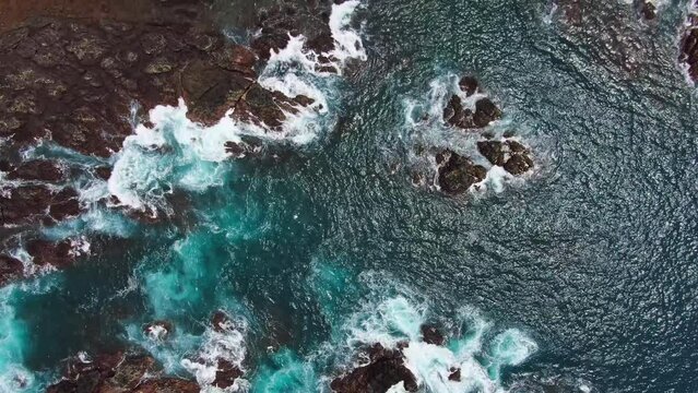 Beautiful Turquoise Blue Ocean Water With White Waves Crashing Into Rocky Coast. HD Aerial Birds Eye View.