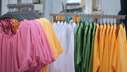 Bright summer clothes to wear on vacation on the beach on a hot summer day. Sale of simple clothes for daily use. Sale of bright jakes and blouses made of cotton with different colors. - obrazy, fototapety, plakaty