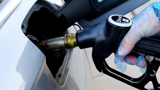 Refueling the car.Refueling pistol in the hands of a man in a blue glove.A man fills up a car tank with diesel fuel. Fuel price in Europe. High quality 4k footage