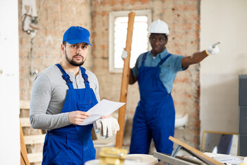 Portrait of upset construction worker getting fired at renovating building, irritated foreman on background