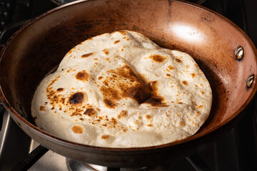 Cooking Tandoori Roti in frying pan, a typical flatbread and popular in West, Central and South Asia.