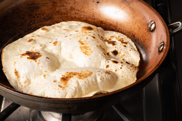 Cooking Tandoori Roti in frying pan, a typical flatbread and popular in West, Central and South...