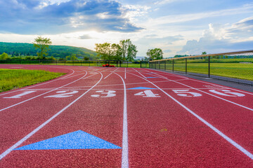 Fototapeta premium late afternoon photo of new running track before first turn, with clouds and sun low on the horizon.