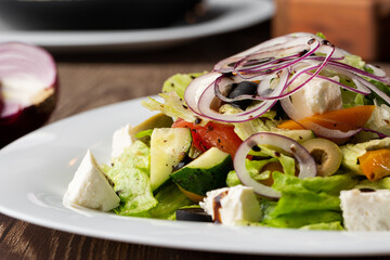 Greek salad with fresh vegetables: tomato, cucumber, red bel pepper, lettuce, onion, olives and...