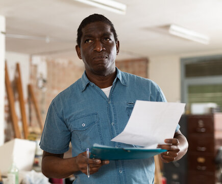 Portrait of african american man engineer with documents inspecting construction site inside apartment.