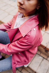 young woman in bright pink leather jacket and jeans. stylish urban image. bright clothes. unrecognizable face. selective focus