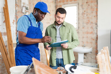 African american builder working on a construction site indoors signs documents from the engineer