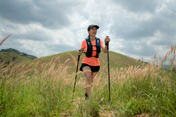 Young women active trail running across a meadow on a grassy trail high in the mountains in the...