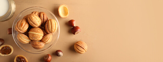 Bowl of tasty walnut shaped cookies with boiled condensed milk on color background with space for text