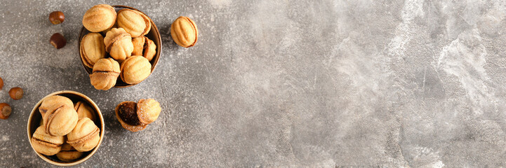 Bowls of tasty walnut shaped cookies with boiled condensed milk on grunge background with space for text