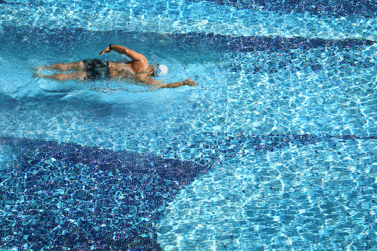 Aerial view of a man swimming  in a pool on hot sunny day.
