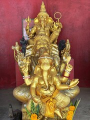 गणेश भगवान की मूर्ति Ganesha figures on an old red wall background. Antique statue God Ganesh. Three golden statues of Ganesha sitting one after another. Hinduism religion, Indian deity. Rich symbol.