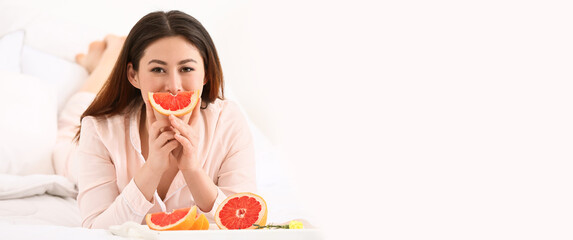 Morning of young Asian woman eating grapefruit in bedroom. Banner for design