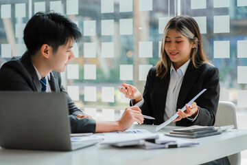 Two young Asian businessmen discuss business in a conference room brainstorming ideas for a successful modern office startup.