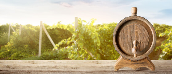 Naklejka premium Wooden barrel of wine on table in vineyard