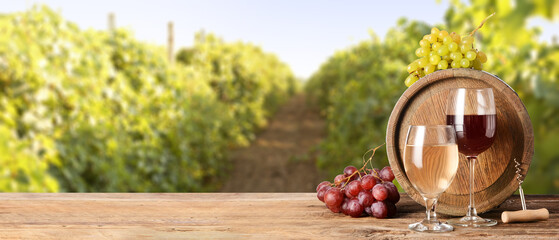 Fototapeta na wymiar Wooden barrel and glasses of wine on table in vineyard