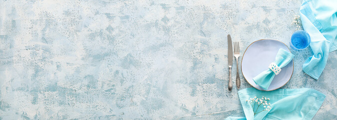 Beautiful table setting in light blue colors on grunge background with space for text