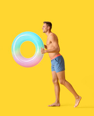 Going young man with inflatable ring on yellow background