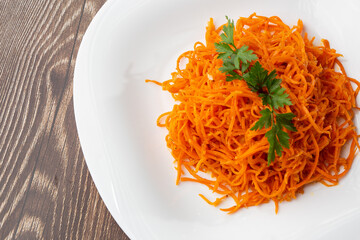Delicious and spicy carrot spaghetti. Delicious spicy juicy bright Korean carrots on a wooden background. Asian cuisine