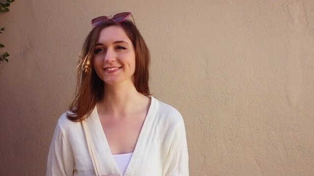 Innocent young girl smiling against a wall