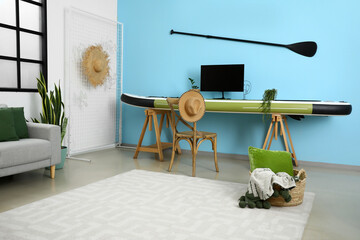 Interior of modern room with sofa and sup surfing board near color wall