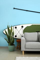 Sofa and board for sup surfing near color wall in room